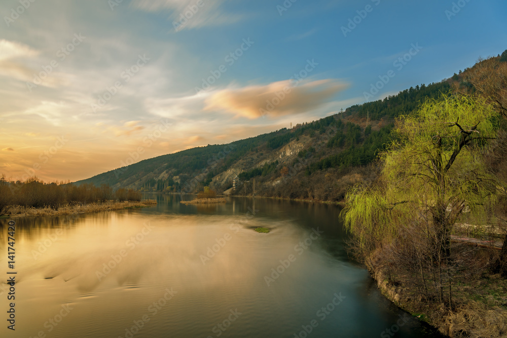 Sunset on the lake with forest with green grass