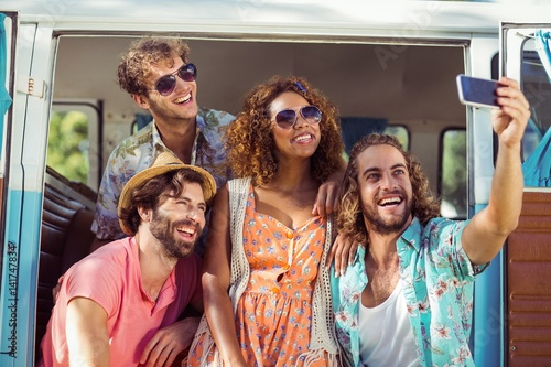 Group of happy friend taking a selfie in campervan
