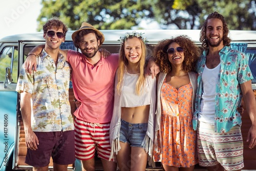 Group of happy friends standing together near campervan