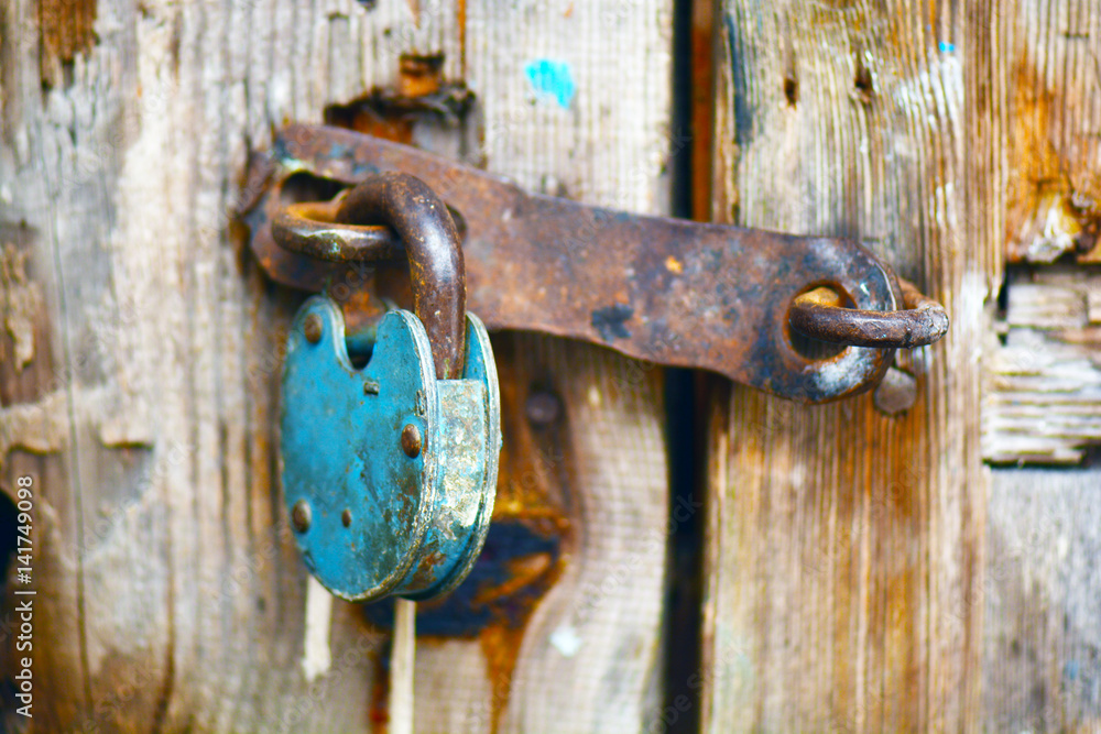 Old rusty padlock hanging on an old wooden door Old rusty padlock hanging on an old wooden door