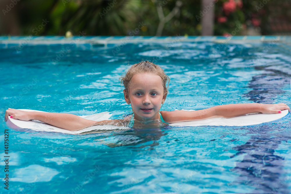 Kids in swimming pool. Children swim outdoors. Toddler child during vacation in a tropical resort with palm trees.