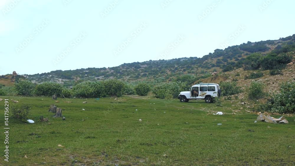 View on travel car on beautiful green valley with rocks. Tourists enjoy the picnic. Pan and static shot. View on travel car on beautiful green valley with rocks. Tourists enjoy the picnic. Pan and static shot.