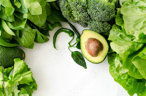 Avocado, salad, broccoli, spinach and pepper on white background. Healthy food concept with fresh assorted green vegetables. Copy space