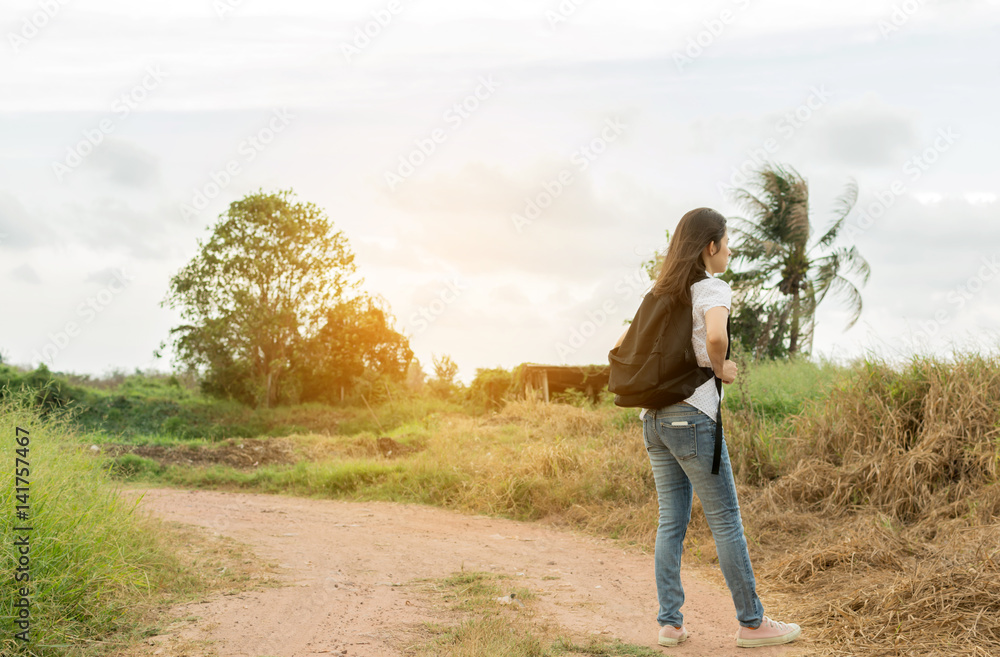 young traveller woman walking along country road.