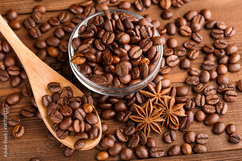 Fototapeta Naklejka Na Ścianę i Meble -  Coffee beans and cinnamon on a background of burlap. Roasted coffee beans background close up. Coffee beans pile from top with copy space for text. Seasoning. Spice. Cinnamon. Badian. Coffee house.