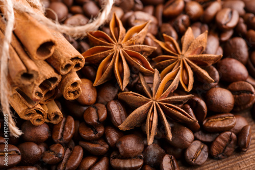 Coffee beans and cinnamon on a background of burlap. Roasted coffee beans background close up. Coffee beans pile from top with copy space for text. Seasoning. Spice. Cinnamon. Badian. Coffee house. © stas_malyarevsky