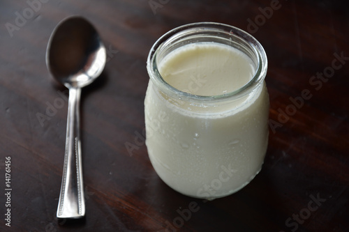 yogurt in a jar with a silver spoon on a wooden table