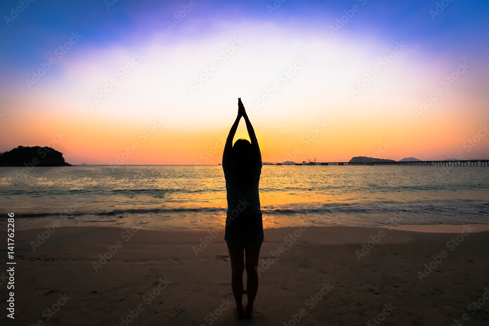Silhouette woman yoga on the beach over the sunset