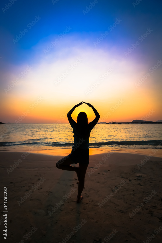 Silhouette woman yoga on the beach over the sunset