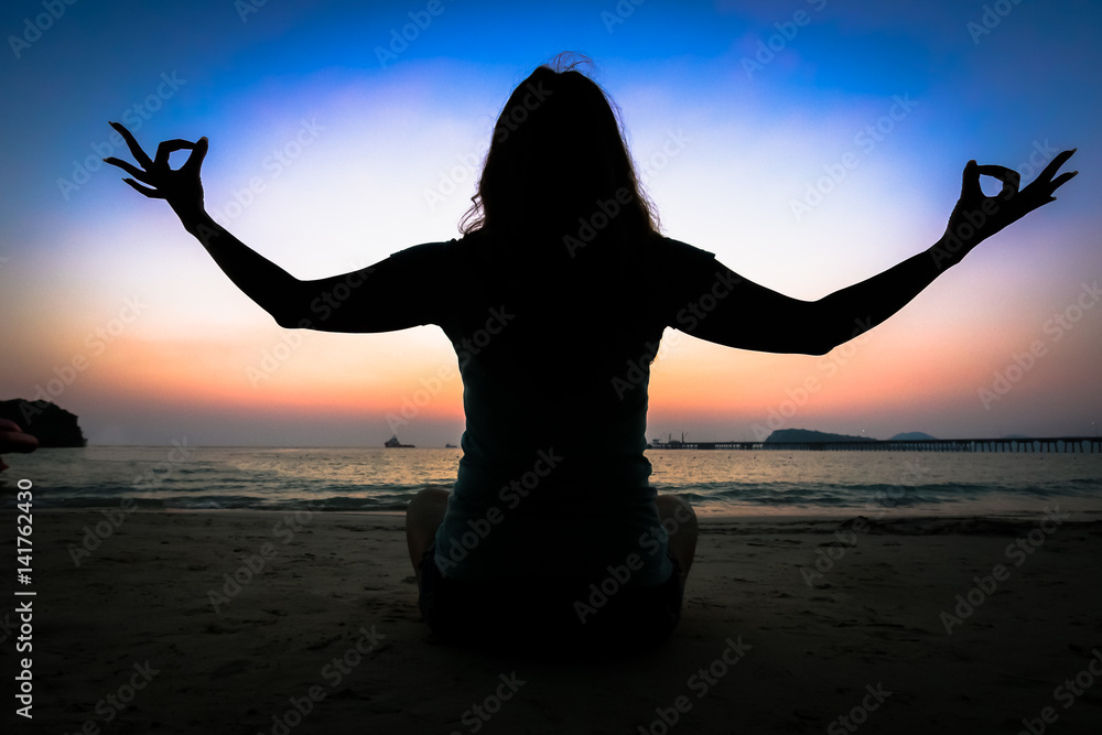 Silhouette woman yoga on the beach over the sunset