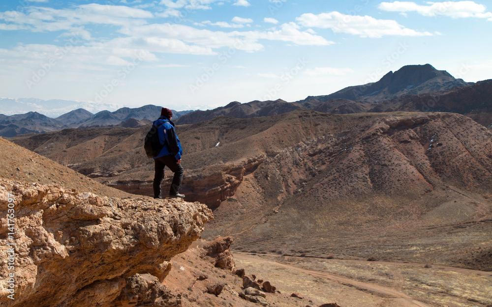Climber over a canyon.
Man standing on a rocky cliff over the Valley of Castles in the Sharyn Canyon National Park, Kazakhstan. Early spring sunny day.