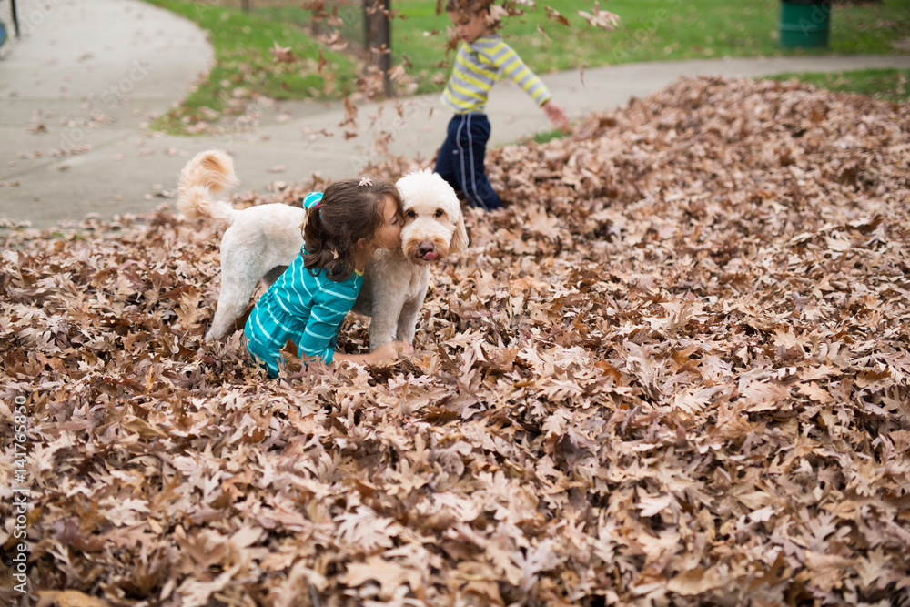 Girl kissing dog on a pile of leaves Girl kissing dog on a pile of leaves