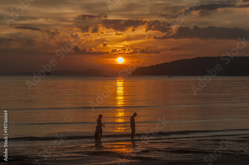Silhouette of family against glorious sunset on the sea, Ao Nang, Thailand
