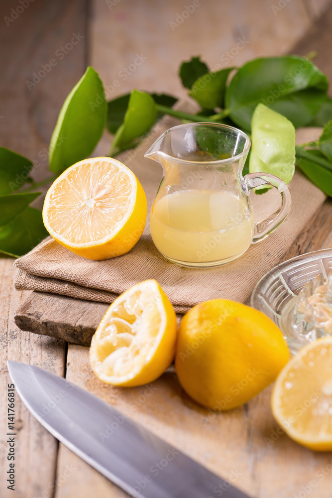 glass bowl of freshly squeezed lemon juice, lemon squeezer and ripe lemons on wooden background glass bowl of freshly squeezed lemon juice, lemon squeezer and ripe lemons on wooden background