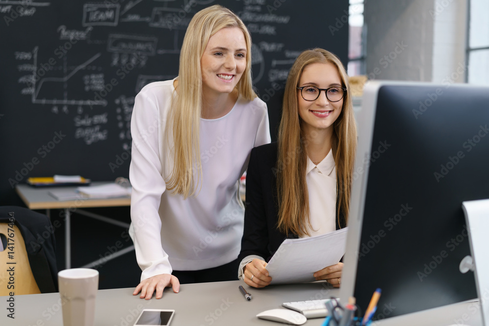 frauen arbeiten zusammen im büro und schauen auf computer frauen arbeiten zusammen im büro und schauen auf computer