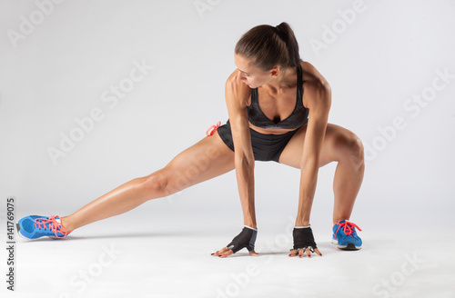 muscular fit young woman doing stretching exercise isolated on studio background