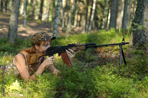 Beautiful girl in the woods with a machine gun Kalashnikov photo