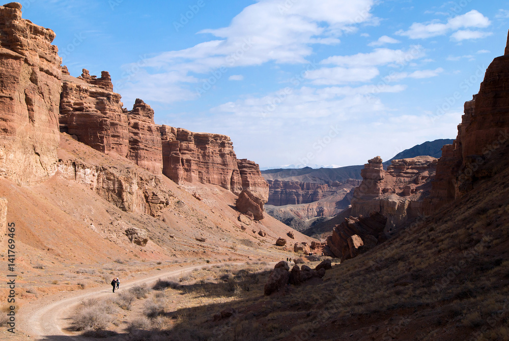 Sharyn Canyon panorama.
View of the Valley of Castles in the Sharyn Canyon National Park, Kazakhstan. Distant hikers are walking along the road. Early spring sunny day.