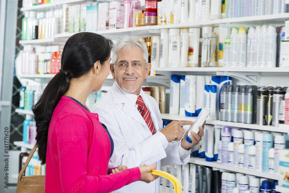 Chemist Looking At Customer While Pointing At Shampoo Bottle