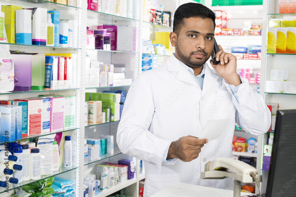 Pharmacist Using Phone While Holding Prescription Paper