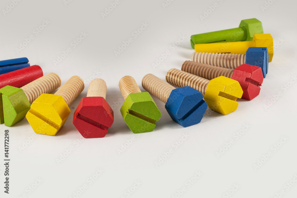 Colorful wooden toy bolts arranged, isolated studio shot on grey gradient background Colorful wooden toy bolts arranged, isolated studio shot on grey gradient background