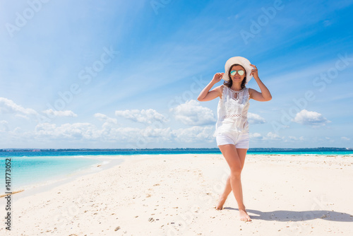 beautiful smiling girl in hat on a beach of blue ocean and sky on the background