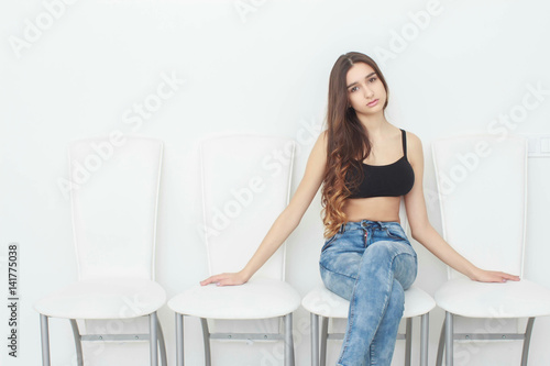 Portrait of a charming young woman posing on the chair isolated on a white background