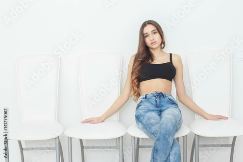Portrait of a charming young woman posing on the chair isolated on a white background