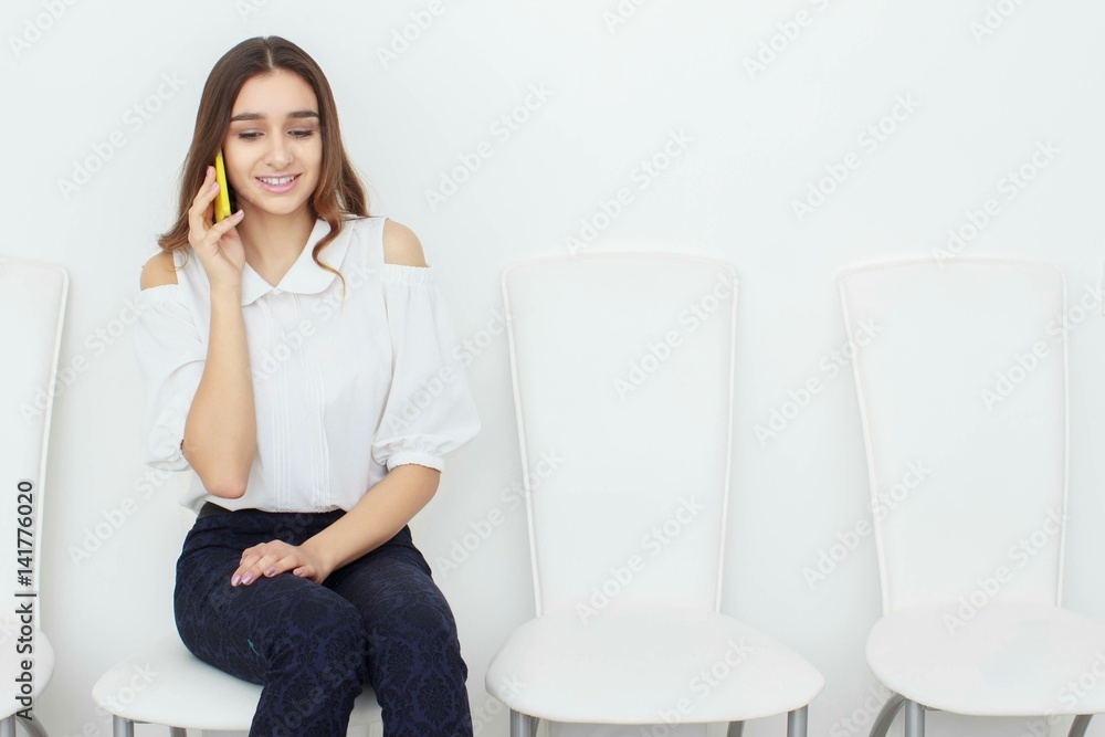 Young business woman sitting on chair and using mobile phone