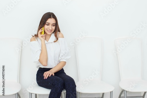 Young business woman sitting on chair and using mobile phone