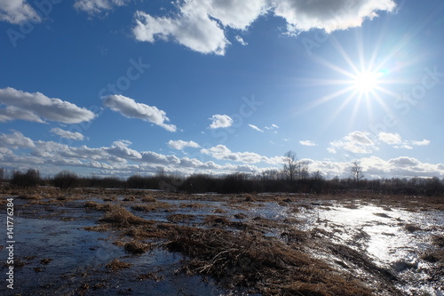 The bright spring sun shining in a blue sky with clouds