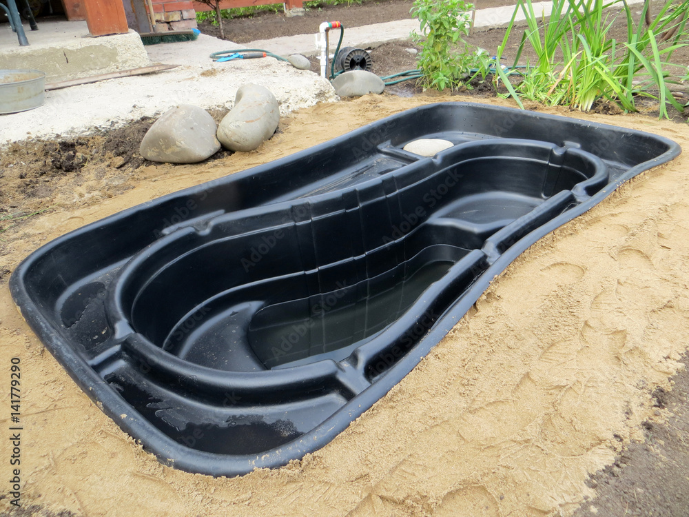 Testing of an installed preformed plastic pond insert filled with some  water in the summer garden Stock Photo | Adobe Stock
