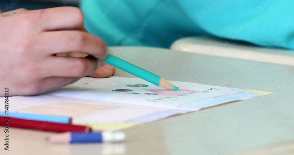 Child uses a teal pencil crayon to shade the white space of a drawing of a heart and sun Child uses a teal pencil crayon to shade the white space of a drawing of a heart and sun