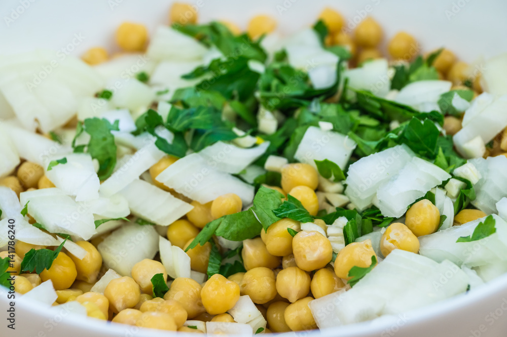 Cheakpeas, onions and leaves of parsley. Close-up image of cooked chickpeas, chopped onion, garlic and fresh parsley in bowl