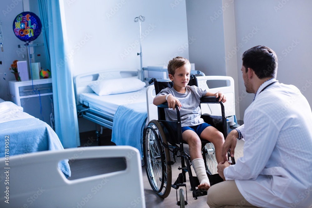 Male doctor interacting with child patient in ward Male doctor interacting with child patient in ward