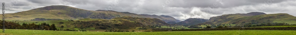 Dry Stone Wall among the green fields with mountain in the background in the Lake District