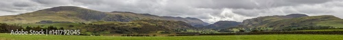 Dry Stone Wall among the green fields with mountain in the background in the Lake District