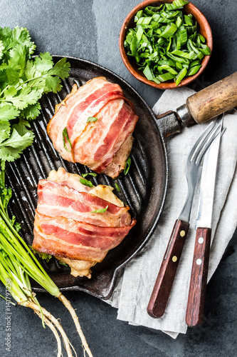 Grilled chicken wrappen in bacon on grill iron pan with herbs. Top view photo