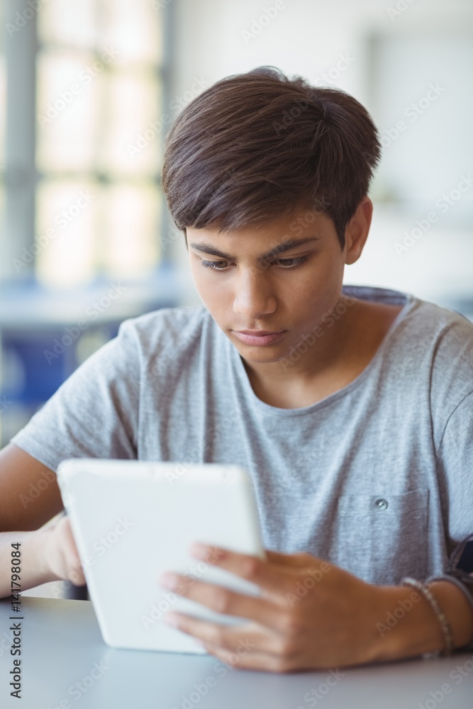 Attentive schoolboy using digital tablet in classroom Attentive schoolboy using digital tablet in classroom