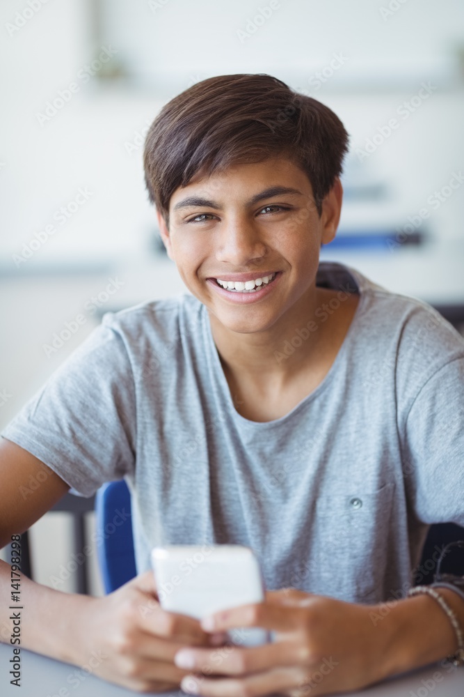 Portrait of happy schoolboy using mobile phone in classroom Portrait of happy schoolboy using mobile phone in classroom
