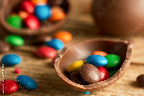 Chocolate easter eggs, with multi-colored sweets drops drops on a wooden background. The concept of a holiday and a happy Easter.