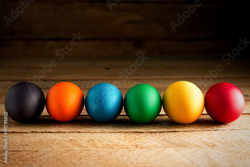 Multicolored easter eggs, on a wooden background, with space for text. The concept of a holiday and a happy Easter.