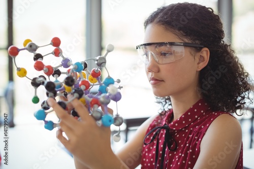 Attentive schoolgirl experimenting molecule model in laboratory photo