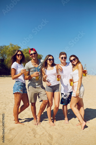 Group of friends hanging out with beer at the beach. Excellent sunny weather. Beautiful figures. Super mood. Summer concept 