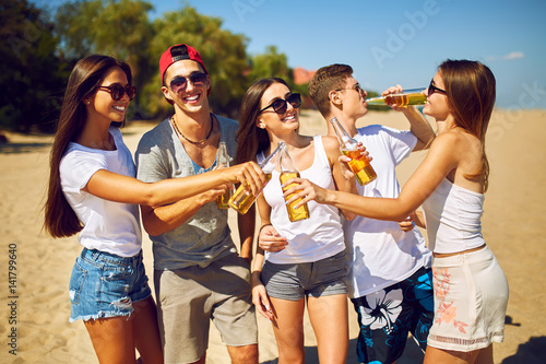 Group of friends hanging out with beer at the beach.  Excellent sunny weather. Beautiful figures. Super mood. Summer concept
