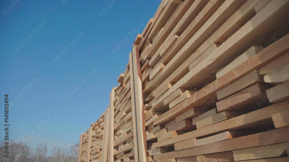 Rows of wooden bars on the street near the production area. Wooden blanks for the production of glued timber stand in the street in neat rows. Wood production of laminated veneer lumber. Rows of wooden bars on the street near the production area. Wooden blanks for the production of glued timber stand in the street in neat rows. Wood production of laminated veneer lumber.