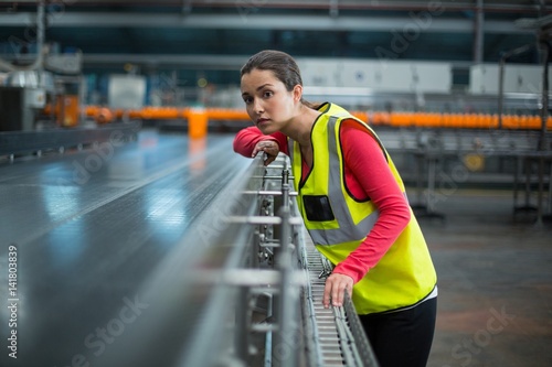 Female factory worker checking conveyor belt photo