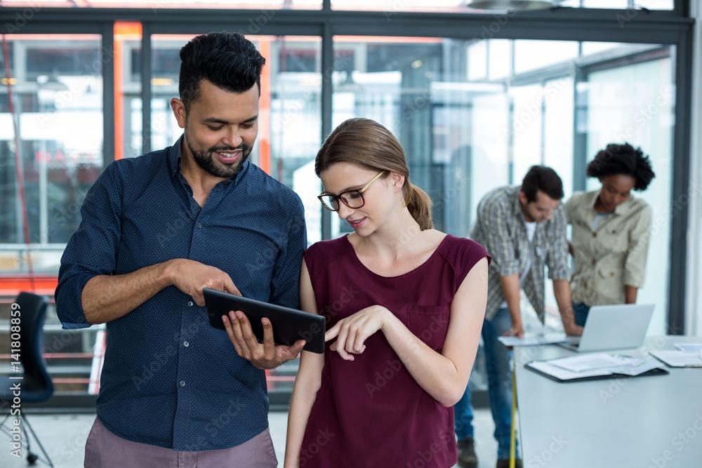 Business executives discussing over digital tablet in meeting Business executives discussing over digital tablet in meeting