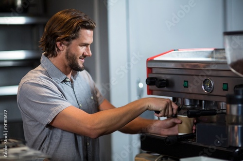 Male staff making cup of coffee at counter
