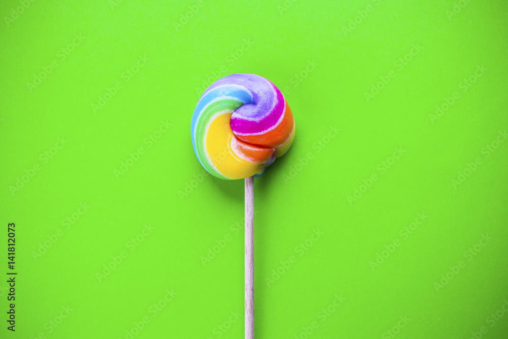 rainbow colored lollipop isolated on green background. copy space rainbow colored lollipop isolated on green background. copy space